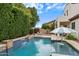 Inviting backyard pool with waterfall feature, covered patio, and lush landscaping for outdoor enjoyment at 16158 W Christy Dr, Surprise, AZ 85379