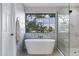 Bright bathroom boasts a soaking tub, tiled walls, and a large window with lush outdoor views at 175 N Brookside St, Chandler, AZ 85225