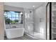 Bright bathroom features a soaking tub, tiled shower, and serene backyard views at 175 N Brookside St, Chandler, AZ 85225