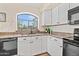 Bright kitchen features white cabinets, black appliances, and a large arched window at 20017 N 65Th Dr, Glendale, AZ 85308