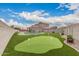Landscaped backyard featuring a swimming pool, putting green, and covered patio at 30878 W Picadilly Rd, Buckeye, AZ 85396