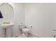 Bright bathroom featuring pedestal sink, toilet, and a round mirror at 30878 W Picadilly Rd, Buckeye, AZ 85396