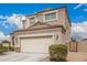 Side view of the house with a two-car garage, beige stucco, and stone accents at 30878 W Picadilly Rd, Buckeye, AZ 85396