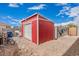 Spacious red shed with a roll-up door, providing ample storage space for tools and equipment at 30878 W Picadilly Rd, Buckeye, AZ 85396