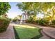 Green backyard featuring a putting green, mature trees, and a pool with an outdoor dining set at 3683 E Nolan Dr, Chandler, AZ 85249