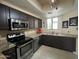 Well-lit kitchen featuring stainless steel appliances, dark cabinets, and granite countertops at 4925 E Desert Cove Ave # 236, Scottsdale, AZ 85254
