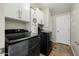 Clean laundry room with modern black washer and dryer, white cabinets and tile flooring at 565 E Rosebud Dr, San Tan Valley, AZ 85143