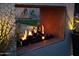 Modern outdoor fireplace feature with black rocks and lush green surroundings at twilight at 5960 E Orange Blossom Ln, Phoenix, AZ 85018