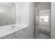 Well-lit bathroom with white cabinetry, a large mirror, and a doorway leading to an adjacent bedroom at 6071 E Artemis Dr, Florence, AZ 85132