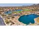 An aerial view of the neighborhood featuring homes surrounding lakes and a golf course with mountains in the distance at 6522 E Night Glow Cir, Scottsdale, AZ 85266