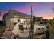Inviting backyard with patio chairs, hot tub, and expansive sliding glass doors to the home's interior under a colorful sunset sky at 6522 E Night Glow Cir, Scottsdale, AZ 85266