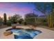 Inviting hot tub with rock accents surrounded by desert landscaping and wrought iron fence under a colorful sunset sky at 6522 E Night Glow Cir, Scottsdale, AZ 85266
