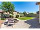 Backyard featuring a paved patio, a central fire pit, and a synthetic grass lawn at 690 W Mangrove Rd, Queen Creek, AZ 85140