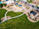 Aerial view of a community playground with colorful play structures, picnic tables, and walking paths amidst green spaces at 690 W Mangrove Rd, Queen Creek, AZ 85140