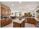 Spacious kitchen with wood cabinetry, granite counters, a large island, and a view into the dining and living areas at 7238 W El Cortez Pl, Peoria, AZ 85383