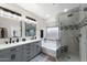 Modern bathroom featuring double sinks, a soaking tub, and a glass-enclosed shower with tiled walls and stone accents at 7554 E Globemallow Ln, Gold Canyon, AZ 85118