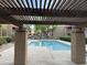 Relaxing pool view under a wooden pergola, complemented by mature trees and lush landscaping at 8260 E Arabian Trl # 275, Scottsdale, AZ 85258