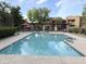Community pool with lounge seating and red umbrella, surrounded by well-maintained landscaping and multi-story building at 8260 E Arabian Trl # 275, Scottsdale, AZ 85258