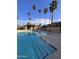 Community pool featuring multiple palm trees, lounge chairs, and an easy access staircase entry at 8260 E Arabian Trl # 275, Scottsdale, AZ 85258