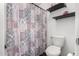 Bathroom highlighting a tiled shower with a decorative curtain, along with a toilet and modern shelving at 844 W Sherri Dr, Gilbert, AZ 85233