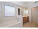 Bright bathroom with a window, soaking tub, wood cabinets, and tile flooring at 9837 W Tonopah Dr, Peoria, AZ 85382