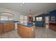 Functional kitchen featuring an island and views into an adjacent Gathering room with a ceiling fan at 9837 W Tonopah Dr, Peoria, AZ 85382