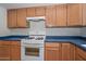 Kitchen area with oak cabinets, blue countertops and white appliances at 9837 W Tonopah Dr, Peoria, AZ 85382