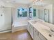 Bright bathroom with a soaking tub, shower, double sink vanity, and large window with a picturesque view at 1360 E Washington Ave, Gilbert, AZ 85234