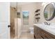 Updated bathroom featuring a tiled shower, dark wood vanity, and a modern round mirror at 15437 S 23Rd Pl, Phoenix, AZ 85048