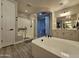 Bathroom featuring a walk-in shower, soaking tub, double sinks, and wood-look flooring at 15620 W Cameron Dr, Surprise, AZ 85379