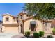 Tan home with stone accents, awning and a well-manicured lawn featuring mature trees at 15620 W Cameron Dr, Surprise, AZ 85379