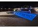 Night-time outdoor pool with a water feature, pool lighting, and patio seating at 15620 W Cameron Dr, Surprise, AZ 85379
