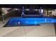 Backyard swimming pool with lighting, landscaping, and waterfall feature for evening enjoyment at 15620 W Cameron Dr, Surprise, AZ 85379