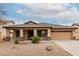 Charming home featuring a two-car garage, covered porch with stone accents, and desert landscaping at 16187 W Gibson Ln, Goodyear, AZ 85338
