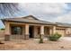 Charming home featuring a two-car garage, covered porch with stone accents, and desert landscaping at 16187 W Gibson Ln, Goodyear, AZ 85338
