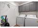 Functional laundry room with washer, dryer, and overhead cabinets for convenient storage at 16187 W Gibson Ln, Goodyear, AZ 85338