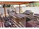 Outdoor kitchen with bar seating, stainless steel BBQ grill under wood pergola with tiled flooring at 1624 E Marigold St, Casa Grande, AZ 85122