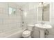 Full bathroom with white tiled walls, vanity sink, toilet, and bathtub at 2019 W Wayland Rd, Phoenix, AZ 85041