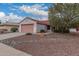 Charming single-story home featuring a two-car garage, desert landscaping and vibrant green trees at 20301 N Queen Palm Ln, Surprise, AZ 85374