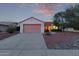 Inviting single-story home featuring a two-car garage and well-maintained desert landscaping under a colorful sunset sky at 20301 N Queen Palm Ln, Surprise, AZ 85374