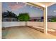A covered patio offers beautiful desert landscaping, block wall, and evening sky at 20301 N Queen Palm Ln, Surprise, AZ 85374
