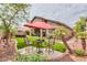 Inviting backyard features outdoor seating and dining space with a vibrant red umbrella, and a hot tub at 20583 N Ryans Trl, Maricopa, AZ 85138