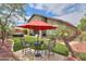 Inviting outdoor seating under a red umbrella, surrounded by lush synthetic turf, and a view of the hot tub at 20583 N Ryans Trl, Maricopa, AZ 85138