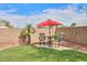 Outdoor seating area with chairs and table under a red umbrella in a well maintained backyard with turf at 20583 N Ryans Trl, Maricopa, AZ 85138