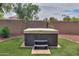 Backyard features a modern hot tub with a neutral-colored cover, complemented by vibrant synthetic grass and privacy fence at 20583 N Ryans Trl, Maricopa, AZ 85138