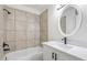 Modern bathroom with tiled shower-tub combination and a sleek vanity with an oval mirror at 2741 E Sweetwater Ave, Phoenix, AZ 85032
