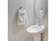 Clean and modern powder room with a pedestal sink, oval mirror, and a hand towel hanging from a silver ring at 30683 W Amelia Ave, Buckeye, AZ 85396