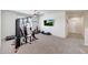 Carpeted gym features a ceiling fan, a TV and several pieces of exercise equipment at 30683 W Amelia Ave, Buckeye, AZ 85396