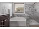 Modern bathroom features a soaking tub, separate shower with marble accents, and natural light at 3907 E Topeka Dr, Phoenix, AZ 85050