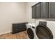 Well-lit laundry room features modern washer and dryer, sink, and dark gray cabinetry at 41424 N Club Pointe Dr, Anthem, AZ 85086